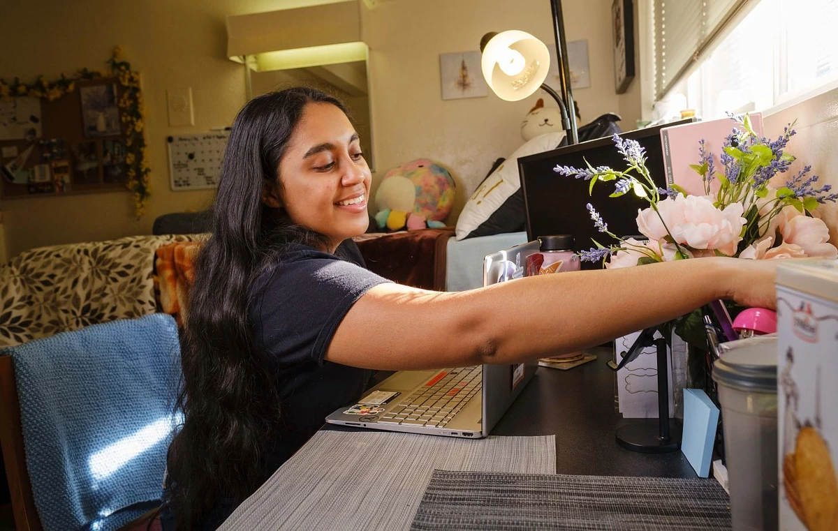 A student sitting at a desk at her University of the Pacific dorm room.