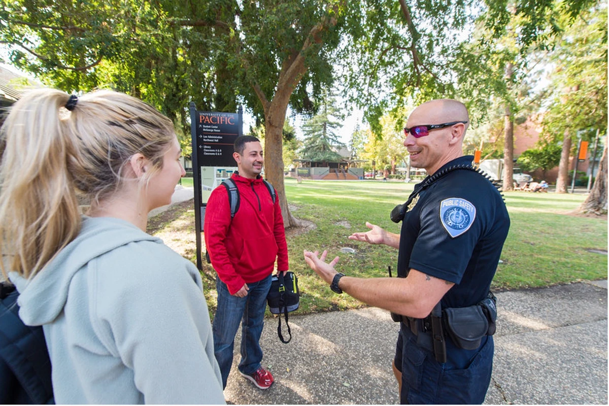 A smiling Police officer talking to two college students